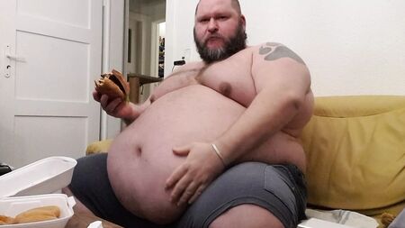 Superchubby SOC: un tipo gordo comiéndose una hamburguesa gigante y aros de cebolla