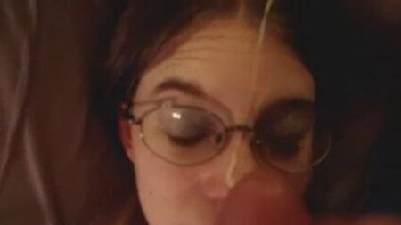Una morena con gafas y aire de empollona recibiendo una gran corrida facial, en primera persona