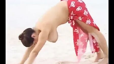 Una mujer con pechos enormes se estira en la playa